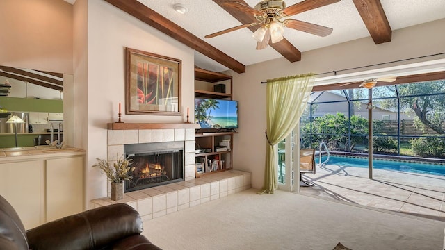 carpeted living room with ceiling fan, a fireplace, a textured ceiling, and vaulted ceiling with beams