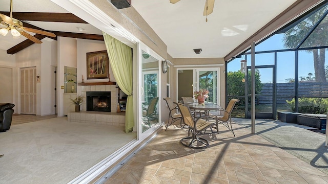 sunroom with ceiling fan, a fireplace, and lofted ceiling with beams