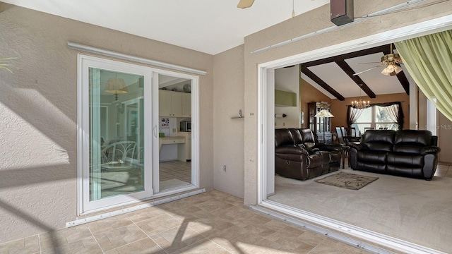 living room with ceiling fan with notable chandelier and vaulted ceiling with beams