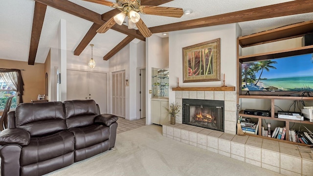 carpeted living room with high vaulted ceiling, beamed ceiling, a tiled fireplace, ceiling fan, and a textured ceiling