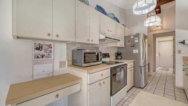 kitchen featuring light tile patterned flooring, appliances with stainless steel finishes, white cabinets, and decorative backsplash