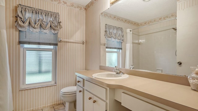 bathroom featuring tile patterned flooring, vanity, toilet, a healthy amount of sunlight, and a textured ceiling