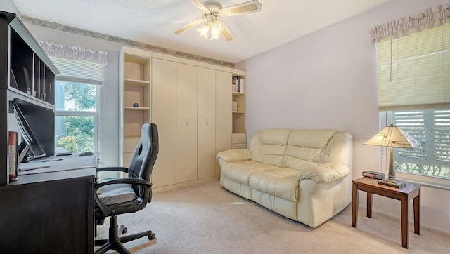 carpeted office space with a textured ceiling and ceiling fan