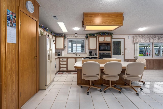 kitchen with light tile patterned floors, black appliances, sink, and a textured ceiling