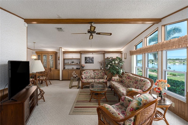 living room featuring crown molding, ceiling fan, a water view, a textured ceiling, and light colored carpet