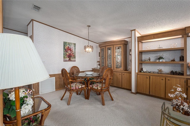 dining area featuring lofted ceiling, a chandelier, light carpet, a textured ceiling, and ornamental molding