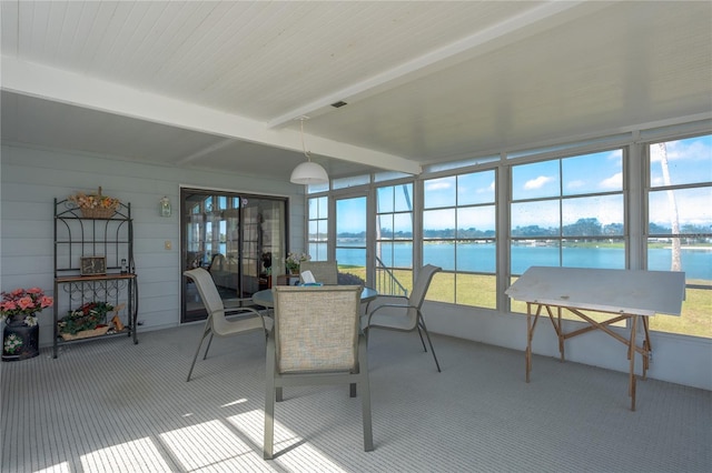 sunroom / solarium featuring beamed ceiling and a water view