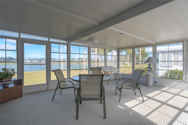 sunroom with beamed ceiling and a water view