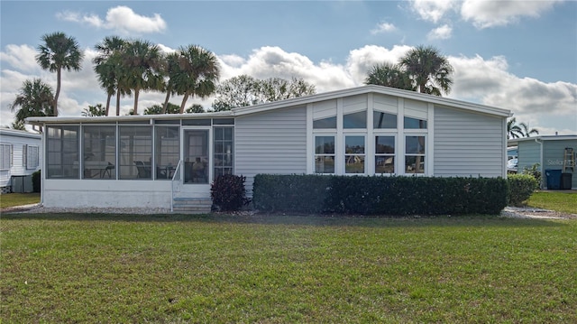 back of house with a sunroom and a lawn