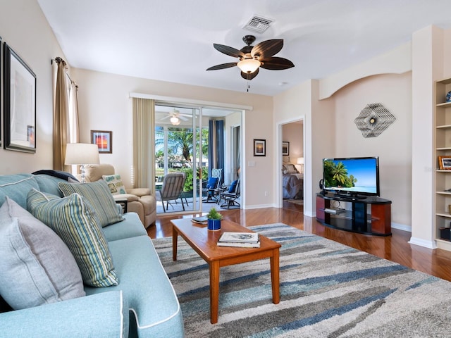 living room with baseboards, visible vents, a ceiling fan, wood finished floors, and built in shelves