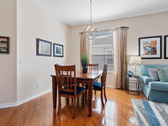 dining area featuring light wood-style flooring, baseboards, and a notable chandelier