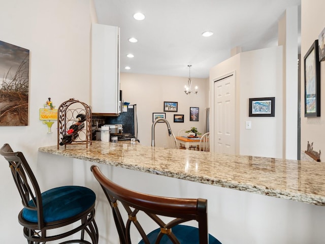 kitchen with light stone countertops, a kitchen breakfast bar, a sink, and recessed lighting