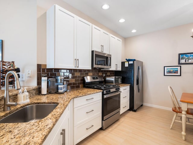 kitchen featuring stainless steel appliances, tasteful backsplash, a sink, and white cabinets