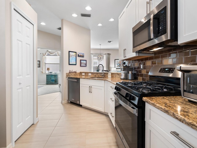 kitchen featuring light stone counters, visible vents, appliances with stainless steel finishes, a sink, and a peninsula