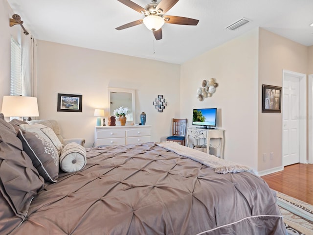 bedroom with baseboards, wood finished floors, visible vents, and a ceiling fan