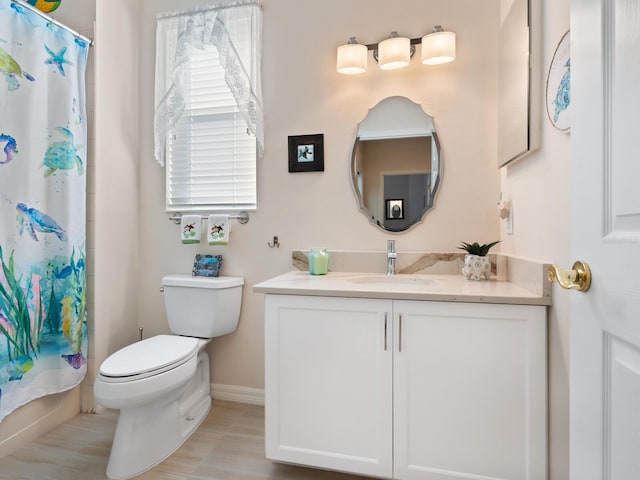 bathroom with baseboards, vanity, and toilet