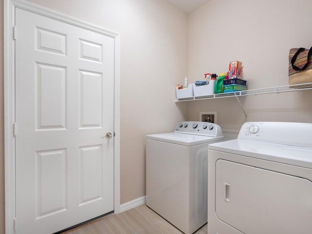 laundry room with laundry area, light wood-style flooring, baseboards, and washer and dryer