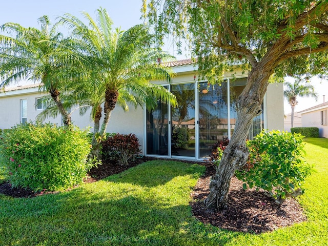 rear view of property with a lawn, a sunroom, and stucco siding