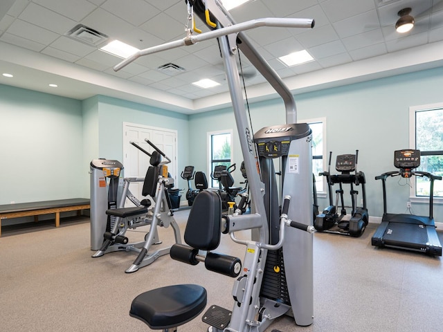 workout area with a drop ceiling, visible vents, and baseboards