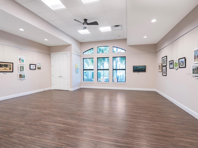 spare room with dark wood finished floors, a drop ceiling, ceiling fan, and baseboards