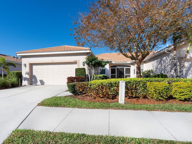 view of front of home with driveway, an attached garage, a tile roof, and stucco siding