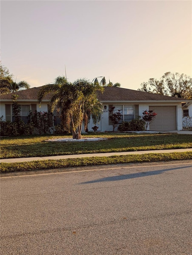 single story home with an attached garage and a front yard