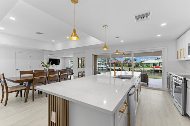 kitchen with pendant lighting, appliances with stainless steel finishes, sink, and an island with sink