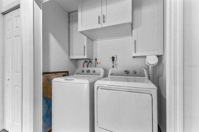 clothes washing area with washing machine and dryer and cabinets