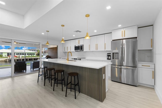 kitchen with white cabinetry, appliances with stainless steel finishes, pendant lighting, and backsplash