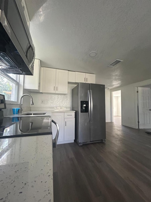 kitchen featuring appliances with stainless steel finishes, white cabinetry, sink, dark wood-type flooring, and a textured ceiling