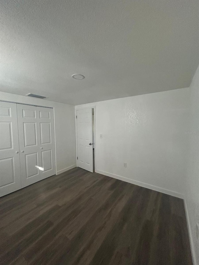 unfurnished bedroom featuring dark hardwood / wood-style flooring, a closet, and a textured ceiling