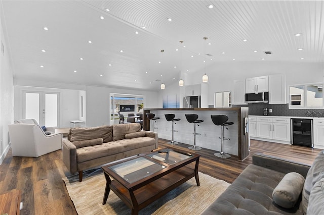 living room featuring french doors, wood-type flooring, beverage cooler, and vaulted ceiling