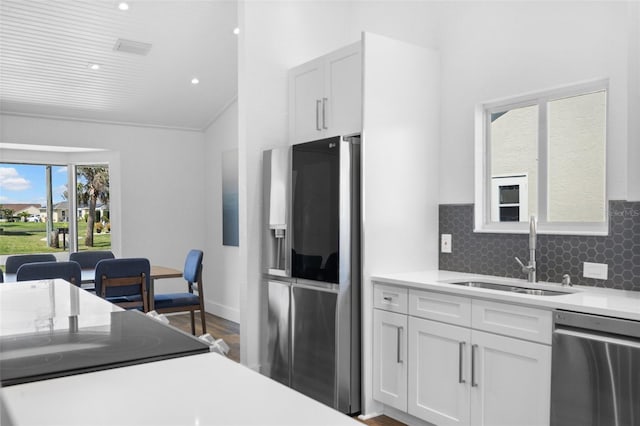 kitchen featuring sink, white cabinetry, backsplash, stainless steel appliances, and wood-type flooring