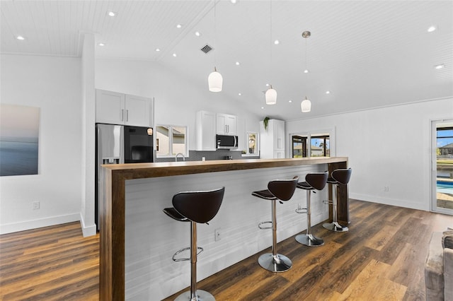 kitchen featuring stainless steel appliances, dark wood-type flooring, a kitchen bar, and decorative light fixtures