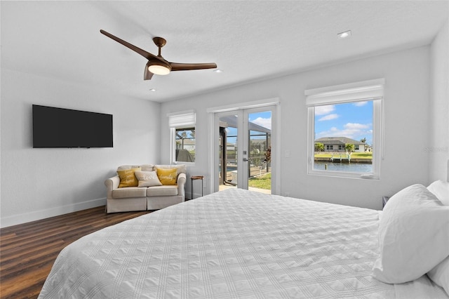 bedroom featuring a water view, hardwood / wood-style floors, multiple windows, and access to outside