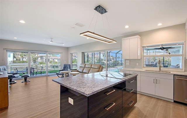 kitchen with ceiling fan, open floor plan, stainless steel dishwasher, white cabinetry, and a sink