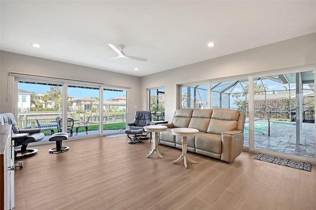 living area featuring ceiling fan, light wood-type flooring, a sunroom, and recessed lighting