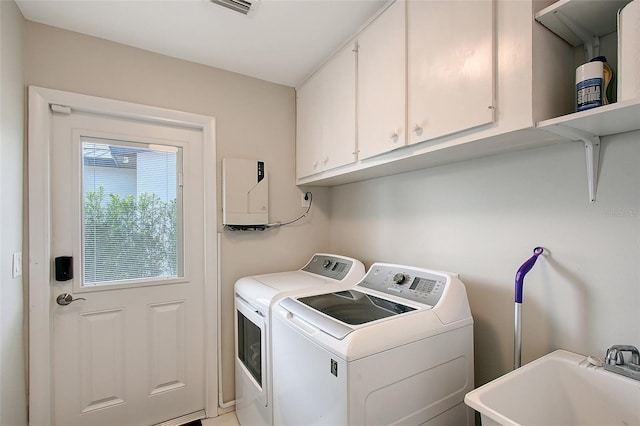 laundry area featuring washing machine and dryer, cabinet space, a sink, and visible vents