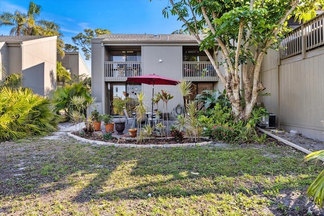 rear view of house with a balcony and a yard