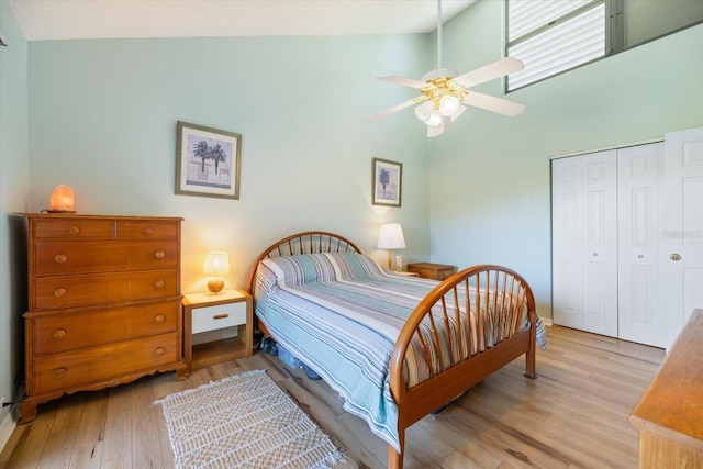 bedroom with light hardwood / wood-style flooring, high vaulted ceiling, a closet, and ceiling fan