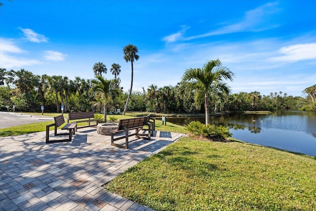 view of home's community with a patio, a water view, a yard, and an outdoor fire pit