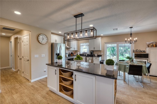 kitchen with stainless steel appliances, a kitchen island, pendant lighting, and white cabinets