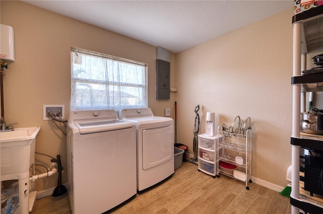 laundry area with sink, washer and clothes dryer, light hardwood / wood-style floors, and electric panel