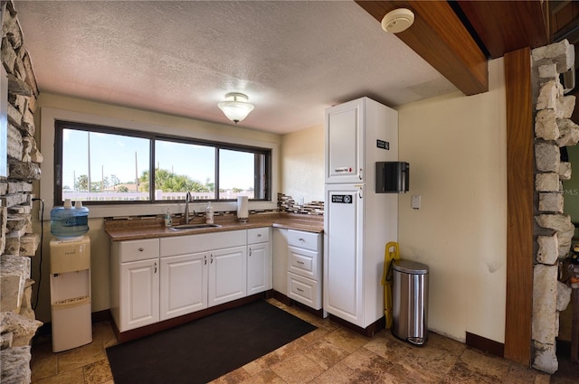 kitchen with white cabinetry, sink, and a textured ceiling