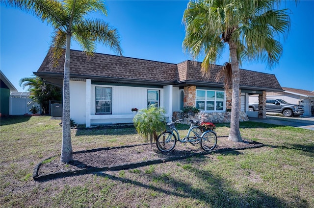 13575 Martha Ave, Port Charlotte, FL 33981 - view of front of house featuring roof with shingles, a carport, a front lawn, central AC unit, and stone siding