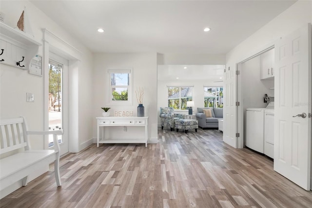 interior space with plenty of natural light, light hardwood / wood-style floors, and washing machine and clothes dryer