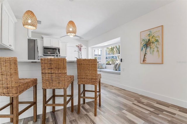 dining space featuring light wood-style flooring and baseboards