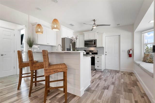 kitchen with visible vents, a kitchen breakfast bar, backsplash, stainless steel appliances, and a peninsula