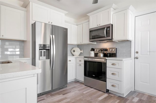 kitchen featuring white cabinetry, decorative backsplash, stainless steel appliances, and light hardwood / wood-style floors