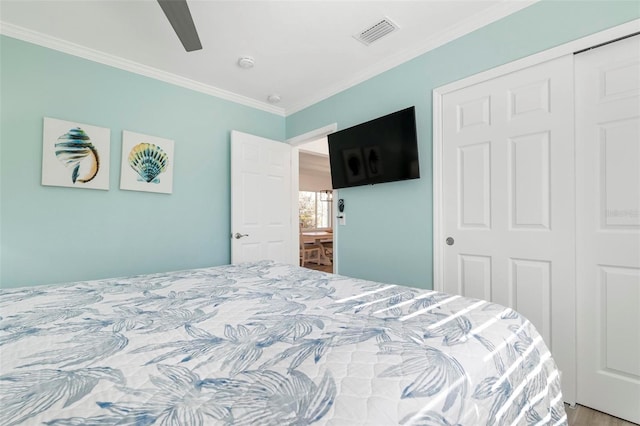 bedroom with wood finished floors, a ceiling fan, visible vents, a closet, and crown molding